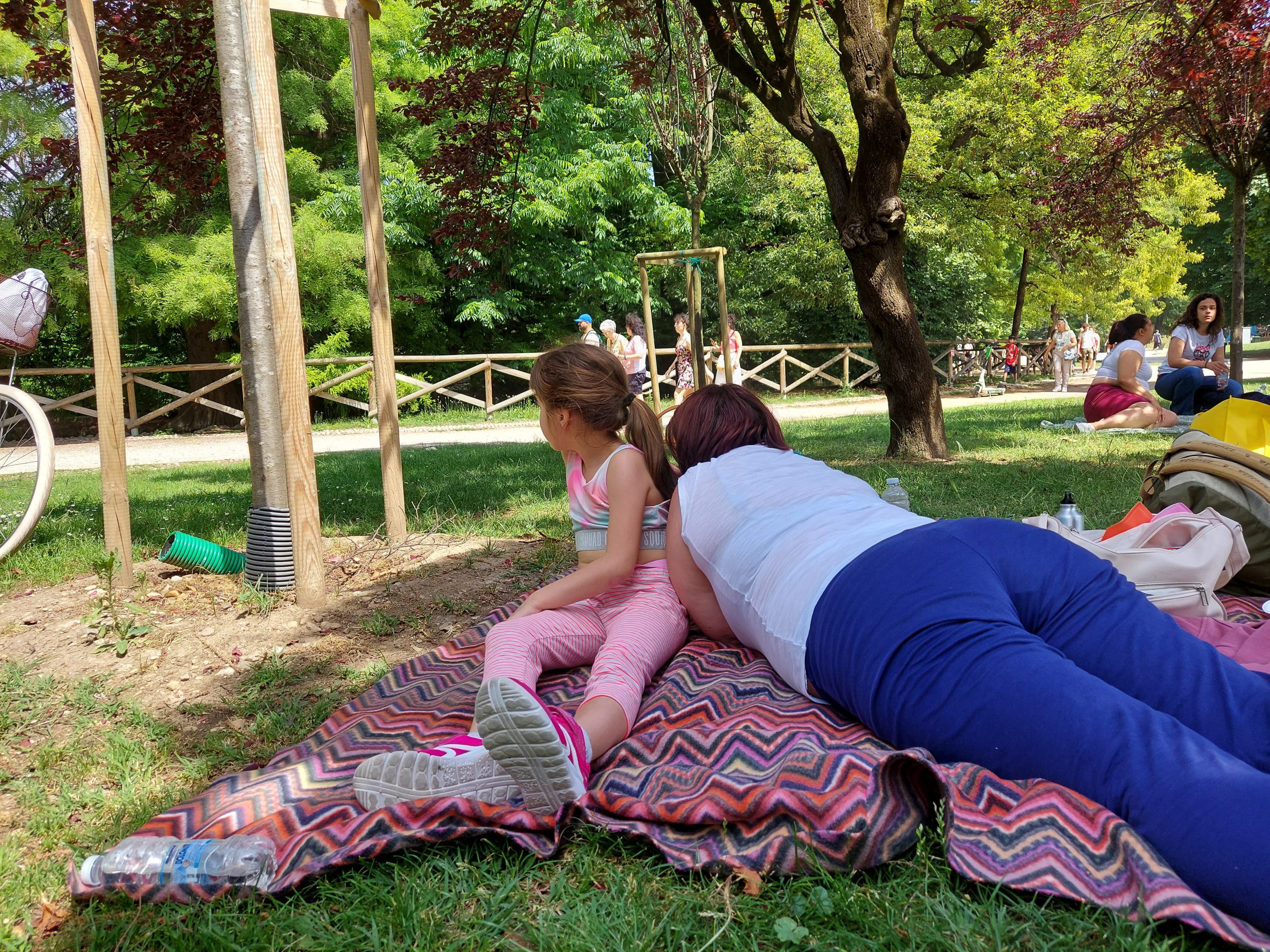 Bambina e signora sdraiati all'ombra in un parco Oltre la casa-famiglia
